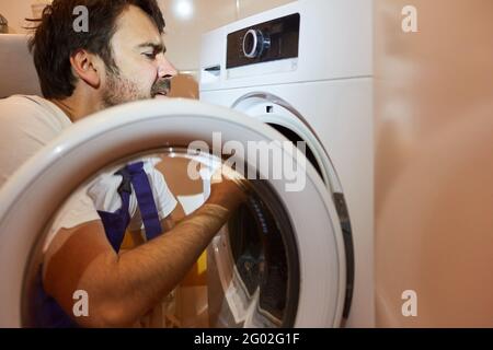 A plumber or plumber from the emergency repair service repairs a tumble dryer Stock Photo