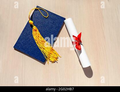 Academic cap and graduation diploma scroll and tied with red ribbon on ...