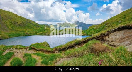 summer landscape with lake on high altitude. beautiful scenery of fagaras mountain ridge in summer. open view in to the distant peak beneath a fluffy Stock Photo