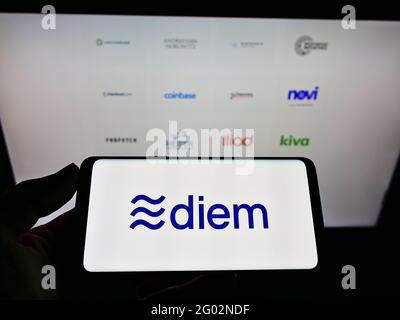 Person holding smartphone with logo of cryptocurrency organization Diem Association on screen in front of webpage. Focus on cellphone display. Stock Photo