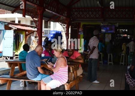 Restaurant Carriacou Caribbean Island sit sitting food eat eating inside bar alcohol stall stalls man lady tourist tourists drink drinks floor boards Stock Photo