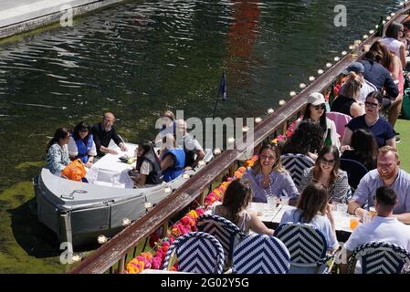 People enjoy the hot weather at the canal in Paddington Basin, north London, as Bank Holiday Monday could be the hottest day of the year so far - with temperatures predicted to hit 25C in parts of the UK. Picture date: Monday May 31, 2021. Stock Photo