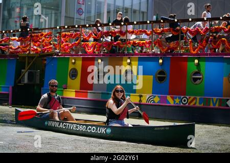 A couple enjoy the hot weather in a canoe on the canal in Paddington Basin, north London, as Bank Holiday Monday could be the hottest day of the year so far - with temperatures predicted to hit 25C in parts of the UK. Picture date: Monday May 31, 2021. Stock Photo