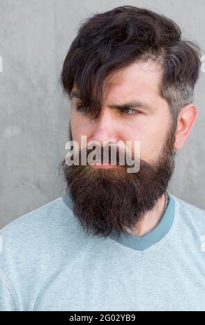 My hair speaks for itself. Serious guy wearing shaped beard and styled hair.  Hairy hipster with stylish beard and mustache hair on grey wall. Bearded  man with unshaven face hair and trendy