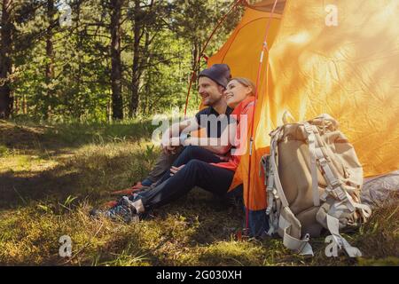 camping trip - young couple sitting in tent at campsite and relaxing after hike Stock Photo