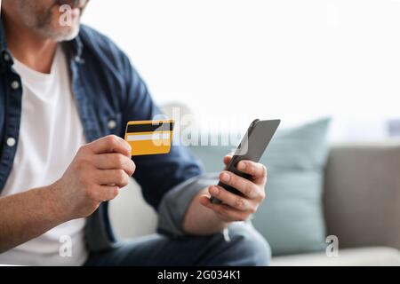 Unrecognizable man using smartphone and holding credit card Stock Photo