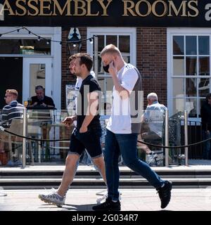 Epsom Surrey London UK, May 31 2021, Three Young Men Walking Past A Wetherspoon’s Pub With People Drinking On An Outside Terrace As Covid Restrictions Stock Photo