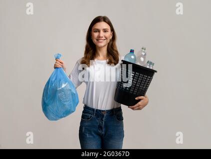 Waste Separation. Woman Carrying Garbage Bag And Bucket Filled With Plastic Bottles Stock Photo