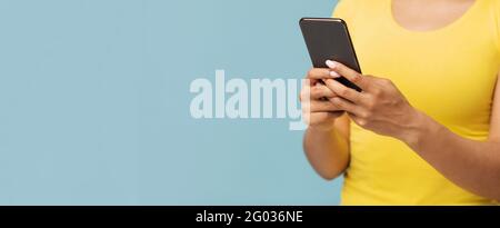 Gadget addiction concept. African american woman using smartphone over blue studio background, panorama with empty space Stock Photo