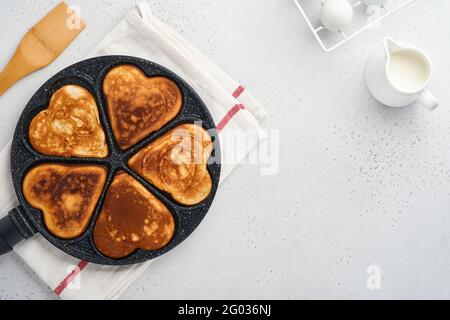 kes in shape of breakfast hearts in the frying pan with ingredients for cooking. Healthy breakfast or snack. Breakfast for Valentines Day.Top view cop Stock Photo