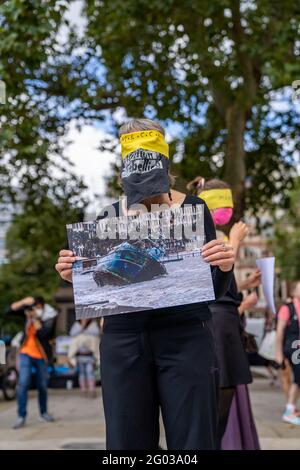 LONDON, UK – Circa September 2020: Extinction Rebellion protestors hold images of natural disasters caused by climate change during a demonstration Stock Photo