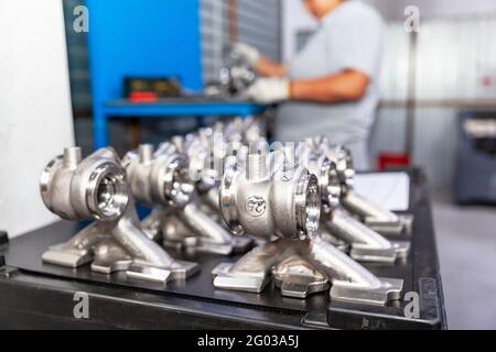 New parts of a car manufactured in the factory, blurred automotive worker at work Stock Photo