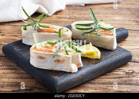 Rolls of thin pita bread and red salted salmon with lettuce leaves on a wooden cutting Board. Copy space Stock Photo