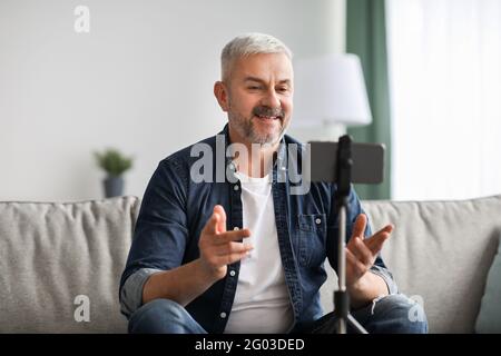 Smiling senior man vlogger broadcasting from home Stock Photo