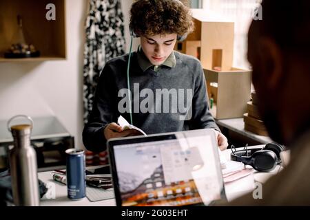Teenage boy studying while father working on laptop at desk Stock Photo