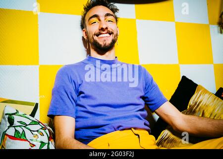 Portrait of smiling young man sitting in apartment Stock Photo