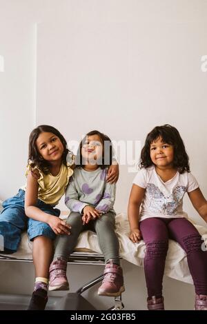 Portrait of happy girls sitting on examination table at medical clinic Stock Photo