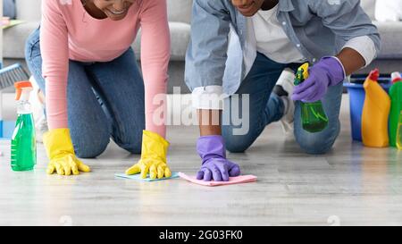 Unrecognizable black man and woman cleaning floor in living room Stock Photo