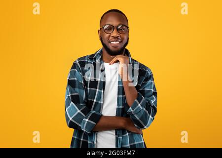 Positive African American Man Wearing Eyeglasses Posing Over Yellow Background Stock Photo