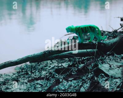 Tiger on dark light color grading at river bank side hunting wildlife toy animal presentation Stock Photo