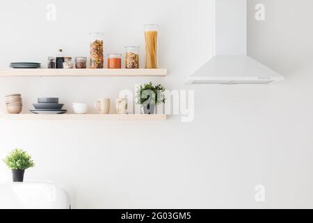 Cooking hood, spices and herbs, kitchenware supplies on shelves in kitchen with white interior design, free space Stock Photo
