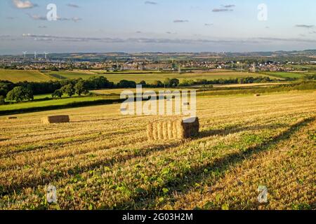 UK, South Yorkshire, Rotherham, Hay Bales in Filed overlooking the town of Wombwell and Village of Brampton Bierlow. Stock Photo