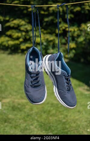 A pair of Sketchers trainers hanging on a washing line after been washed in a washing machine Stock Photo