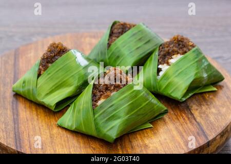 Kuih Pulut inti, traditional Malaysian dessert. Savory glutinous rice with sweetened grated coconut wrapped in banana leaf Stock Photo