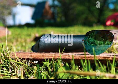 blue sunglasses with a wardrobe trunk on a background of greenery Stock Photo