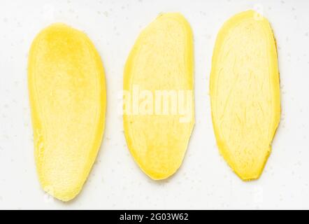 top view of slices of fresh ginger root on gray plate close up Stock Photo