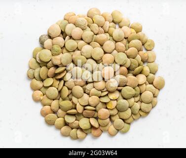 top view of pile of raw whole large green lentils close up on gray ceramic plate Stock Photo