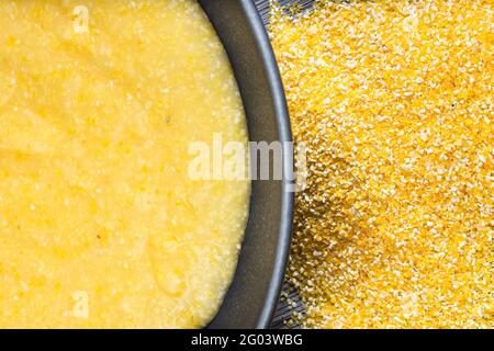 top view of cooked maize porridge in gray bowl and cornmeal gray wooden table Stock Photo
