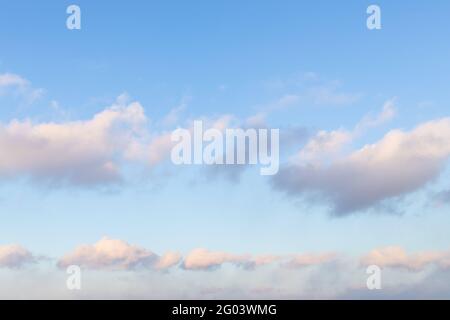 chain of fluffy clouds in blue sunset sky in spring evening Stock Photo