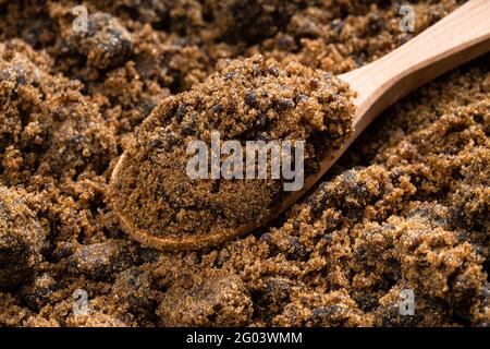 above view of wooden spoon with dark muscovado cane sugar close up on pile of sugar Stock Photo