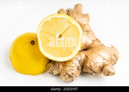 natural fresh whole ginger root and halved lemon fruit on gray plate close up Stock Photo