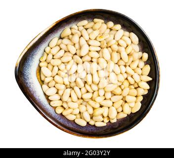 top view of shelled pine nuts in ceramic bowl isolated on white background Stock Photo
