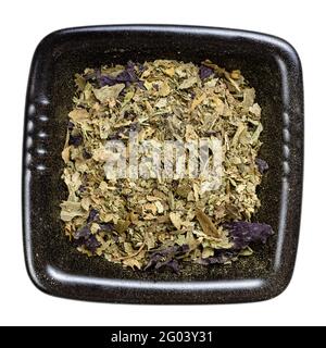 top view of ground leaves of purple and green basil herb in black bowl isolated on white background Stock Photo