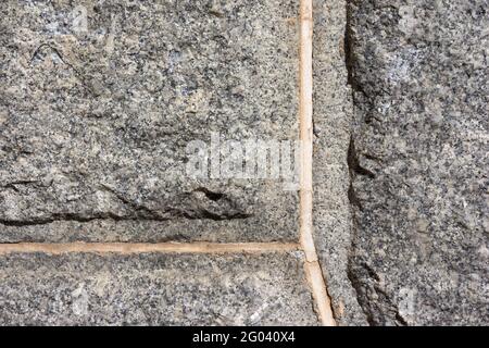 Large joints between the hewn granite stones of a wall in the early morning light. Stock Photo