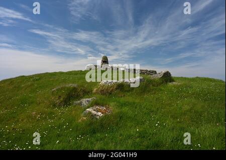 Ruins of Flora MacDonald's birthplace with stones leading to remains of house, memorial cairn and plaque. On grassy hill. Blue sky and light cloud. Stock Photo