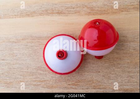 Top view of two red and white plastic fishing bobbers on a wood background. Stock Photo