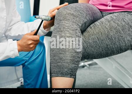 Neurologic examination of reflexes. doctor using a neurological hammer for checking human knee physiological reflex, close-up Stock Photo