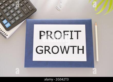 Profit growth text written on white paper above on Notebook. Concept of business success in investment or company revenue more than expense. Stock Photo