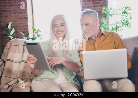 Photo of happy cheerful positive old couple good mood use laptop table sit couch point finger indoor house Stock Photo