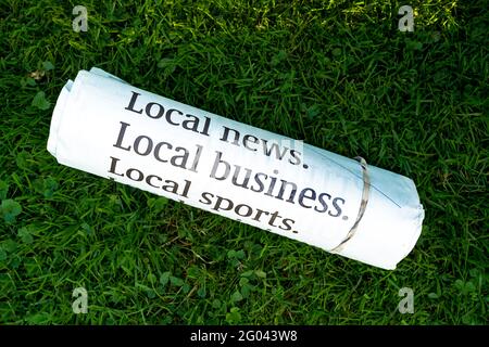 Morning paper rolled up and secured with an elastic laying on the lawn. Stock Photo