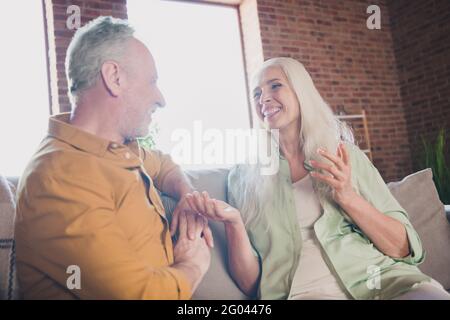 Portrait of nice cheerful couple sitting on sofa talking spending time having fun at modern loft industrial interior home indoor Stock Photo