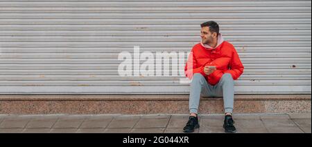 young man sitting on the street with mobile phone Stock Photo