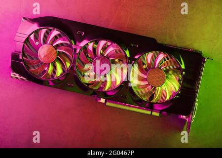 Powerful graphics card with three fans and a futuristic red-green neon backlight. High-tech GPU for gaming and mining of crypto farms Stock Photo