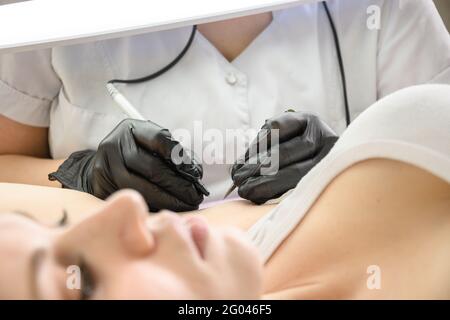 Procedure removal of hair permanently in a woman's armpits using metod electro epilation. Doctor working in cosmetology beauty salon. Close up. Stock Photo
