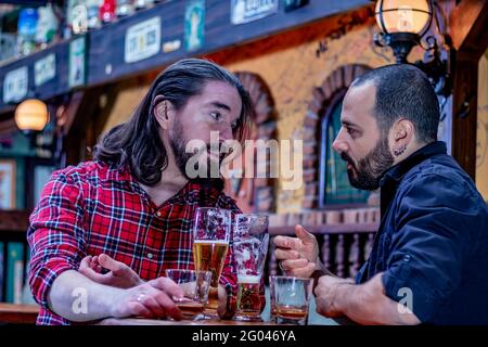 Two male friends drinking whiskey and beer together at the pub. They are drunk and they are talking, and comforting each other. Stock Photo