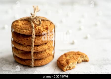Stacks of homemade oatmeal cookies with almonds tied with a rope on a light background with bokeh. Copy space. Close-up. Selective focus. Stock Photo